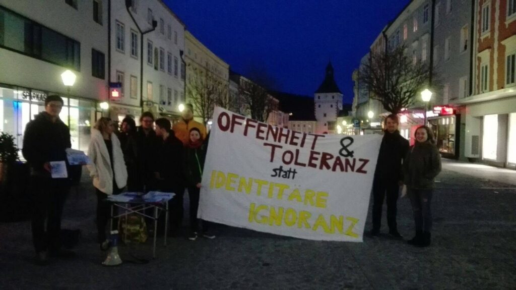 Menschen halten ein Banner am Stadtplatz Vöcklabruck hoch "Offenheit & Toleranz statt Identitäre Ignoranz"