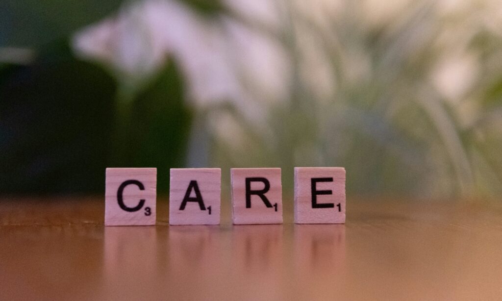 Vier Holzbuchstaben auf denen das Wort Care steht